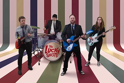 Promotional band photo of The Lucky Shots, striped backdrop session, 2025